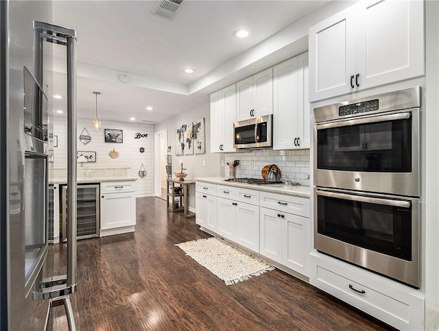 kitchen featuring white cabinets, dark hardwood / wood-style floors, tasteful backsplash, decorative light fixtures, and stainless steel appliances