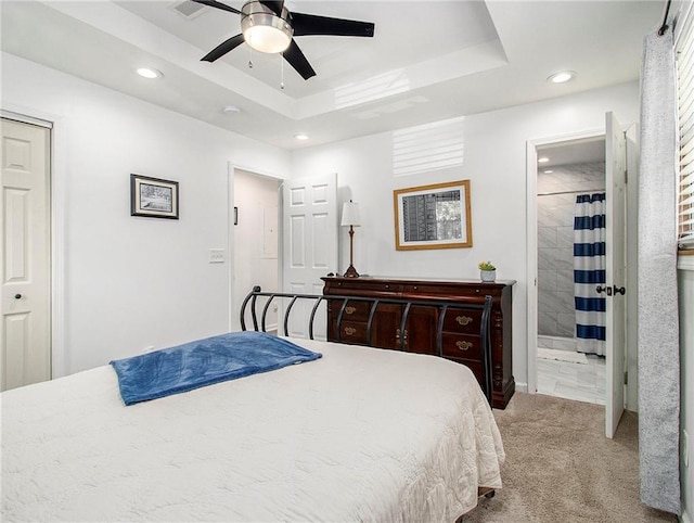 bedroom with a raised ceiling, ceiling fan, light colored carpet, and a closet