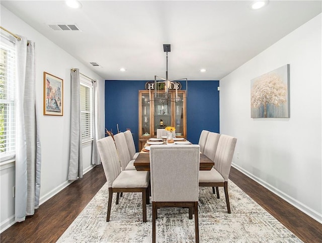 dining space with an inviting chandelier, a wealth of natural light, and dark wood-type flooring