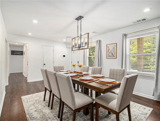 dining area with dark hardwood / wood-style floors and a notable chandelier