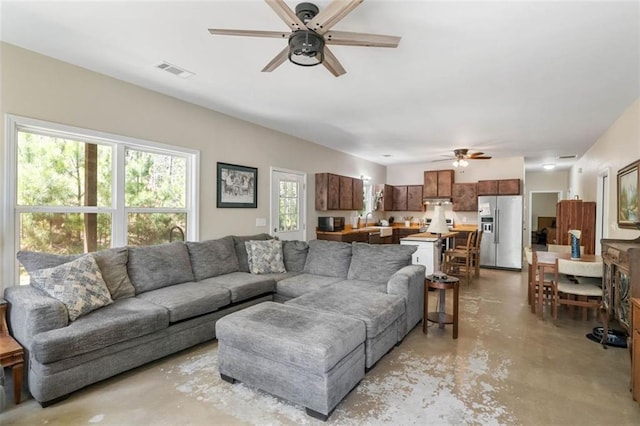 living room with ceiling fan and concrete flooring