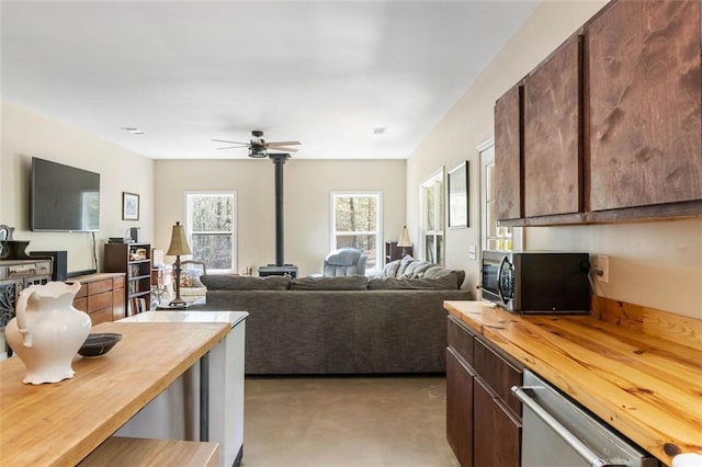 kitchen featuring wood counters, ceiling fan, a wood stove, and appliances with stainless steel finishes