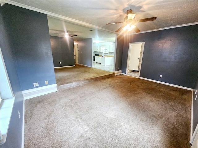 carpeted spare room featuring ceiling fan, ornamental molding, and a textured ceiling