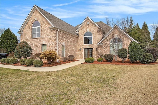 traditional-style house with brick siding, french doors, and a front lawn