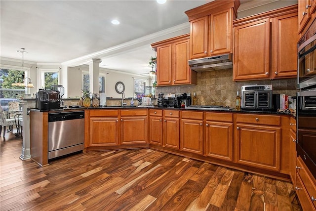 kitchen with crown molding, under cabinet range hood, dark wood finished floors, brown cabinets, and appliances with stainless steel finishes