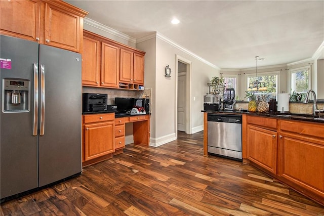 kitchen with a sink, dark wood finished floors, stainless steel appliances, brown cabinetry, and built in study area