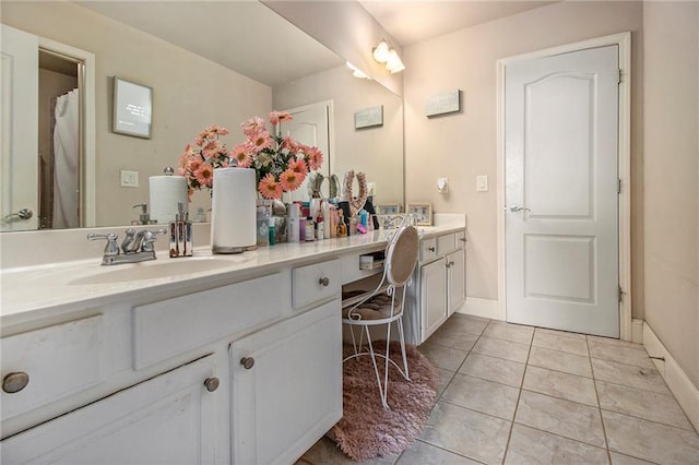 full bathroom with double vanity, baseboards, tile patterned floors, and a sink