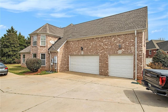 traditional-style home with brick siding, an attached garage, driveway, and roof with shingles