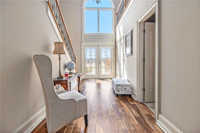 doorway with baseboards, stairway, french doors, a towering ceiling, and wood finished floors