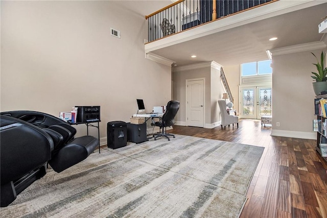 home office featuring visible vents, ornamental molding, a high ceiling, and wood finished floors