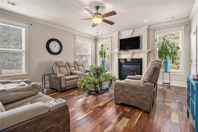 living area with visible vents, dark wood-type flooring, a glass covered fireplace, and ornamental molding