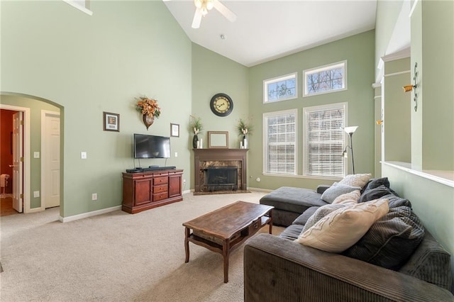 living room featuring a fireplace, light colored carpet, arched walkways, and baseboards