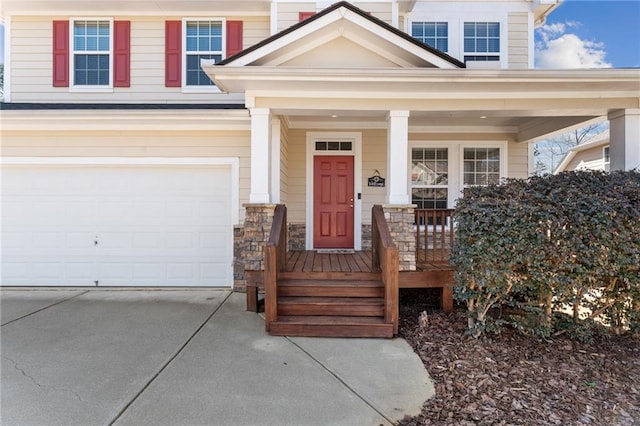 view of exterior entry featuring a porch, concrete driveway, and an attached garage