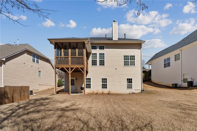 back of house featuring cooling unit, a lawn, a chimney, and a sunroom