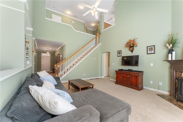 carpeted living area featuring a high end fireplace, stairway, ornamental molding, a high ceiling, and arched walkways