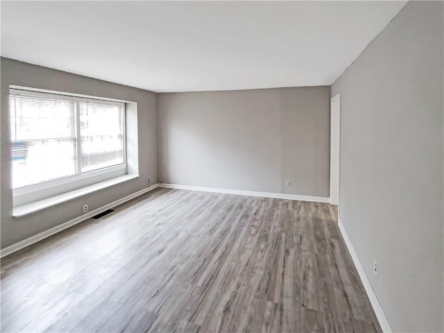 spare room featuring light wood-style floors, visible vents, and baseboards