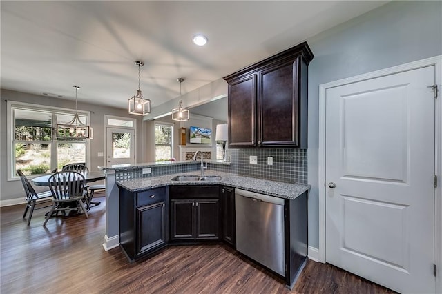 kitchen with decorative light fixtures, sink, stainless steel dishwasher, light stone counters, and kitchen peninsula