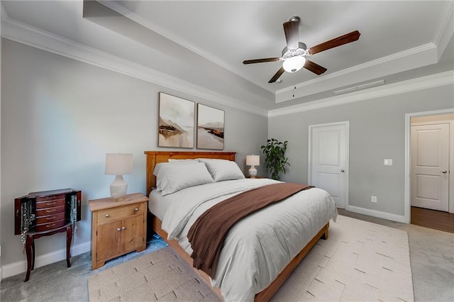 carpeted bedroom featuring ornamental molding, ceiling fan, and a tray ceiling