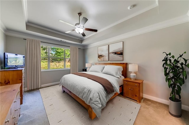 carpeted bedroom with ceiling fan, ornamental molding, and a tray ceiling