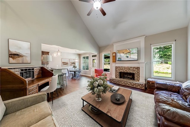 living room featuring ceiling fan, a brick fireplace, hardwood / wood-style floors, and high vaulted ceiling