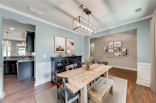 dining area with dark wood-type flooring, ornamental molding, and a chandelier