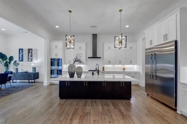 kitchen featuring pendant lighting, a spacious island, stainless steel appliances, and wall chimney range hood