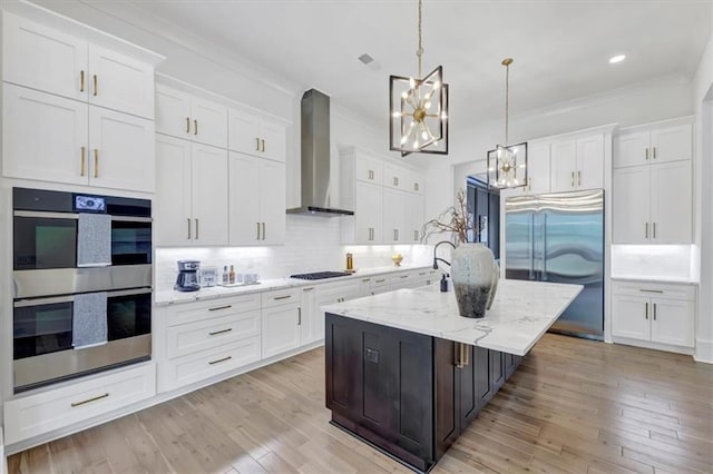 kitchen featuring wall chimney range hood, white cabinets, and appliances with stainless steel finishes