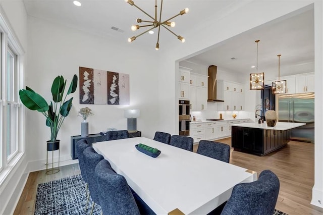 dining space with a wealth of natural light, a notable chandelier, and light hardwood / wood-style flooring