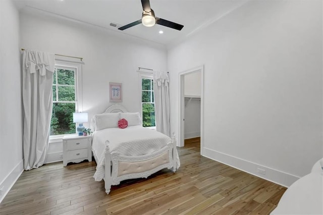 bedroom with light hardwood / wood-style flooring, a walk in closet, ceiling fan, and a closet