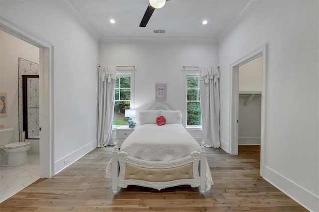 bedroom with light hardwood / wood-style flooring, ceiling fan, a closet, a walk in closet, and ensuite bathroom