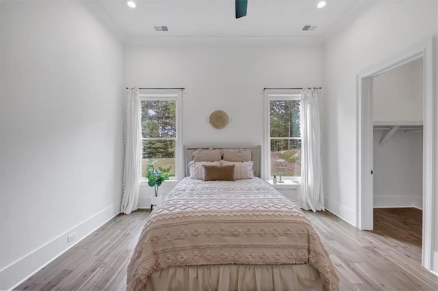 unfurnished bedroom featuring a closet, a spacious closet, multiple windows, and light hardwood / wood-style floors