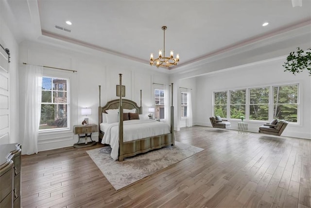 bedroom featuring a tray ceiling, hardwood / wood-style flooring, and a chandelier