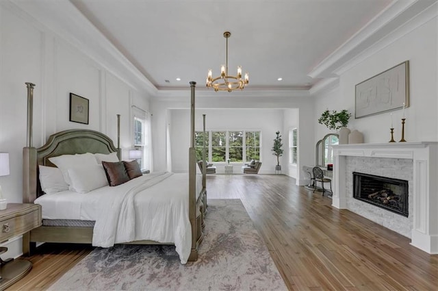 bedroom with a raised ceiling, hardwood / wood-style floors, and an inviting chandelier