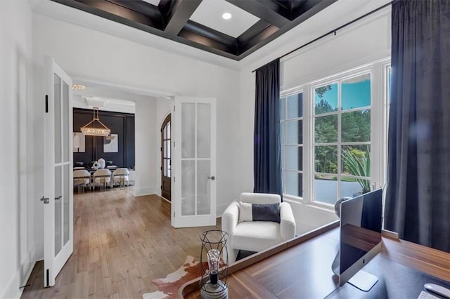 interior space featuring coffered ceiling, light hardwood / wood-style floors, beamed ceiling, and french doors