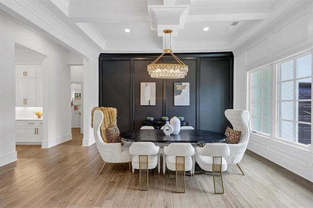 dining space featuring coffered ceiling, an inviting chandelier, crown molding, and light hardwood / wood-style flooring