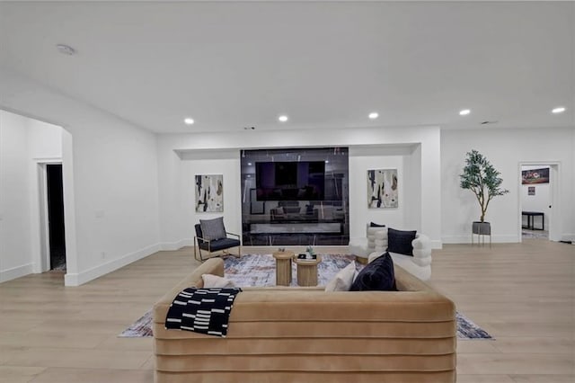 living room with a tile fireplace and light hardwood / wood-style floors