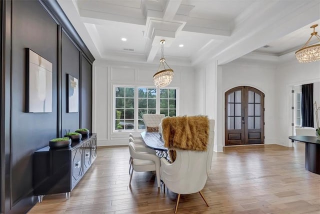 dining space with light wood-type flooring, french doors, crown molding, and a chandelier