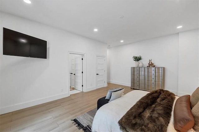 bedroom with ensuite bath and light hardwood / wood-style floors