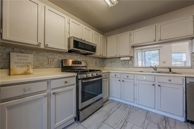 kitchen with sink, white cabinetry, a textured ceiling, and appliances with stainless steel finishes