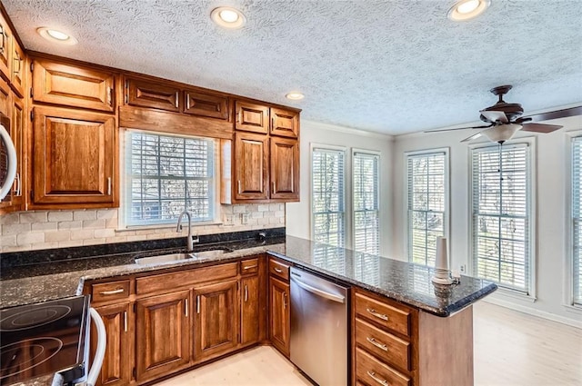 kitchen featuring dishwasher, brown cabinets, a peninsula, electric range, and a sink