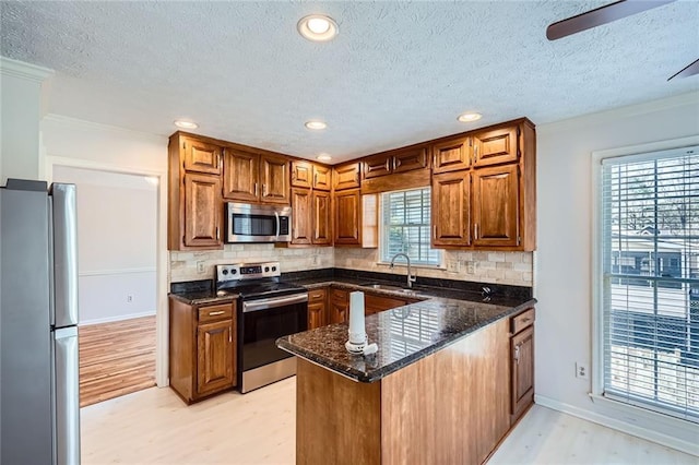 kitchen featuring a sink, tasteful backsplash, appliances with stainless steel finishes, and a peninsula