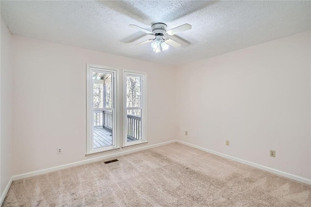 carpeted empty room with visible vents, baseboards, a textured ceiling, and a ceiling fan