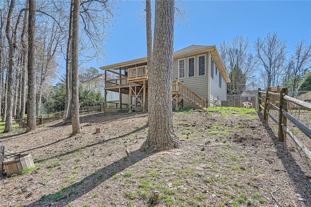 rear view of property with a deck, stairs, and fence