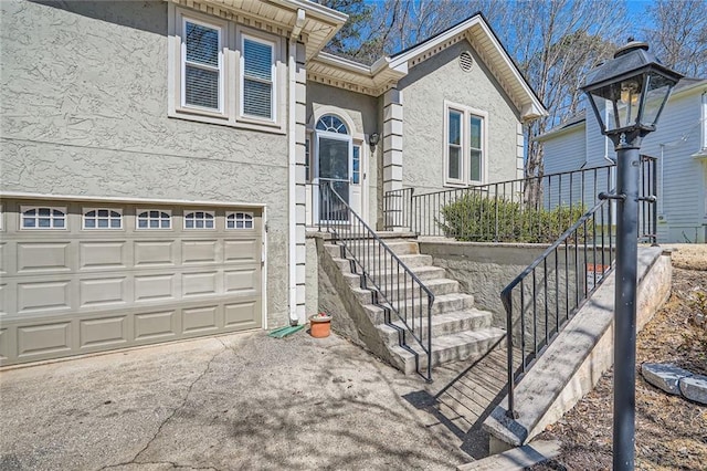 view of front of house with stucco siding, an attached garage, and driveway