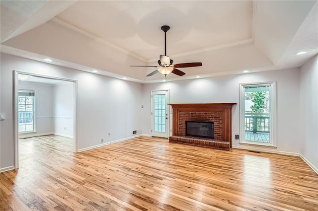 unfurnished living room with light wood-type flooring, a tray ceiling, baseboards, and ceiling fan