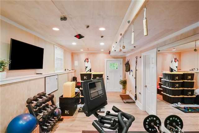 workout room with ornamental molding and light hardwood / wood-style floors