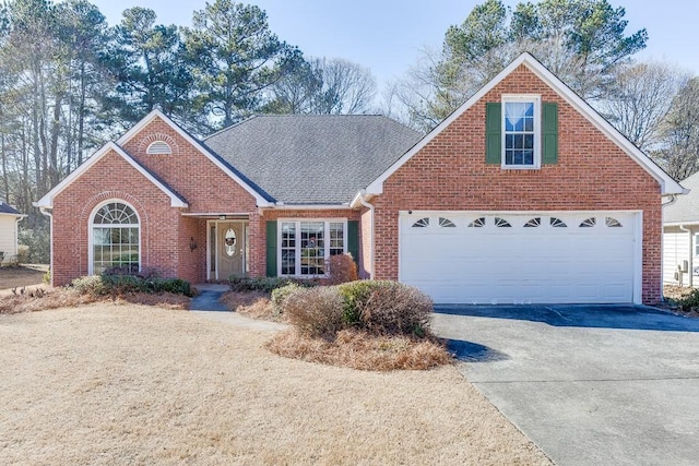 traditional-style house with driveway, brick siding, and roof with shingles