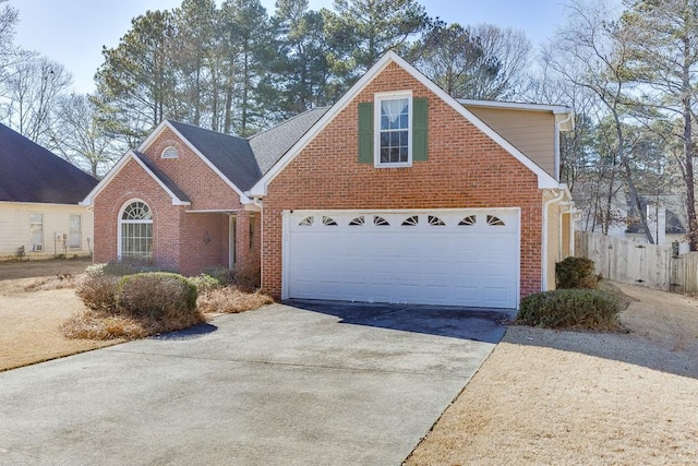 traditional-style house featuring driveway, fence, and brick siding