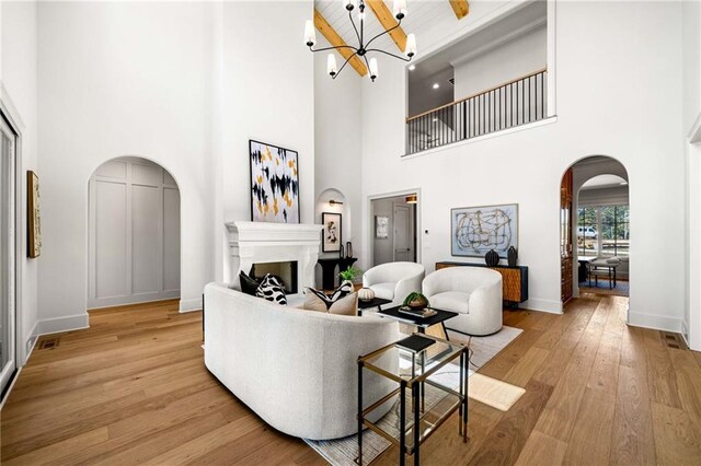 unfurnished living room featuring a high ceiling, beam ceiling, french doors, and light wood-type flooring