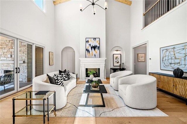 605 Claxton Ln, Milton, GA 30004 - living area with wood finished floors, a fireplace with raised hearth, beamed ceiling, arched walkways, and an inviting chandelier